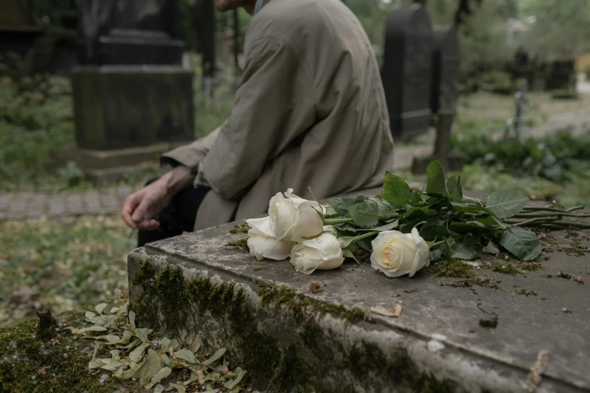 Coroană funerară circulară din flori albe și frunze verzi